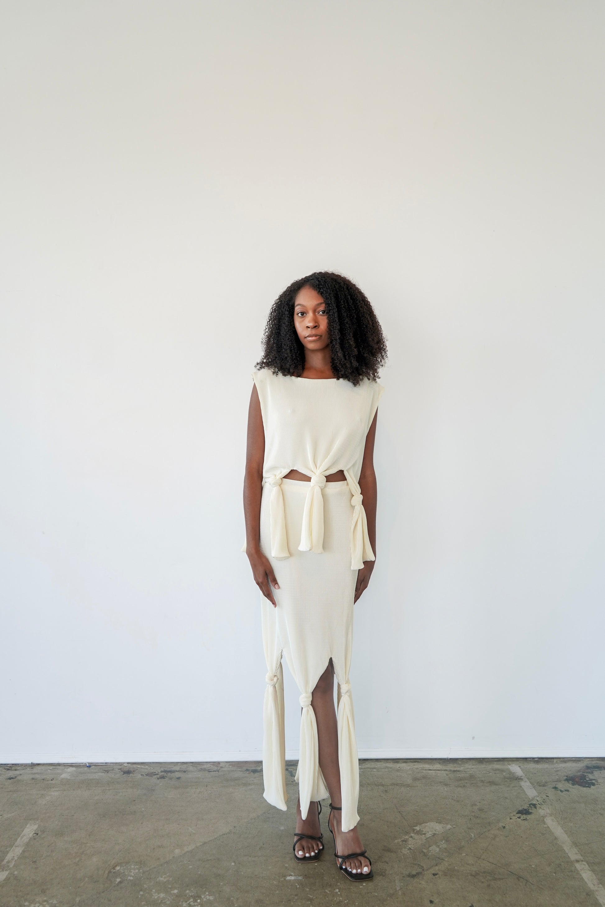 Model wearing Robin Top tied at the waist – pleated crop top with sculptural plissé fabric and boat neck