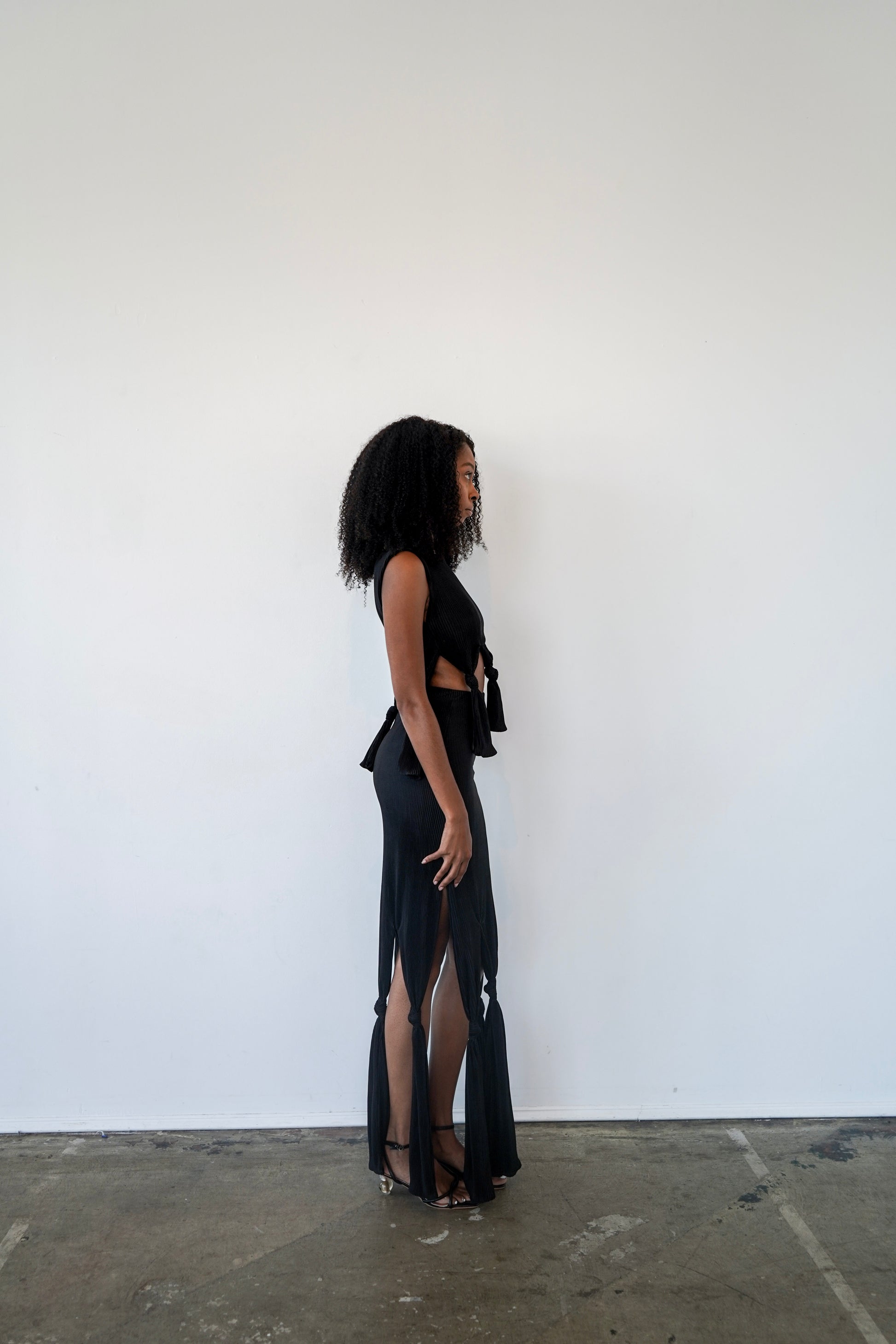 Side view of Robin Top in black – sculptural cropped top in plissé fabric with waist ties and relaxed drape